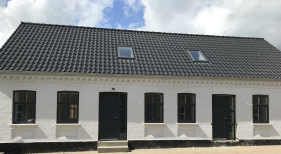 Totalrenoveret dobbelthus med sort tag og sprossevinduer