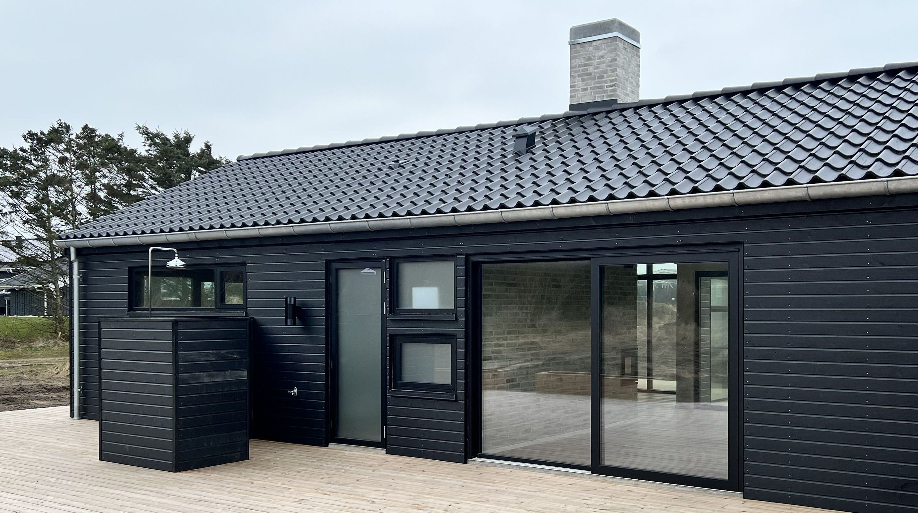 Sort arkitekttegnet sommerhus med store vinduer og godt lysindfald